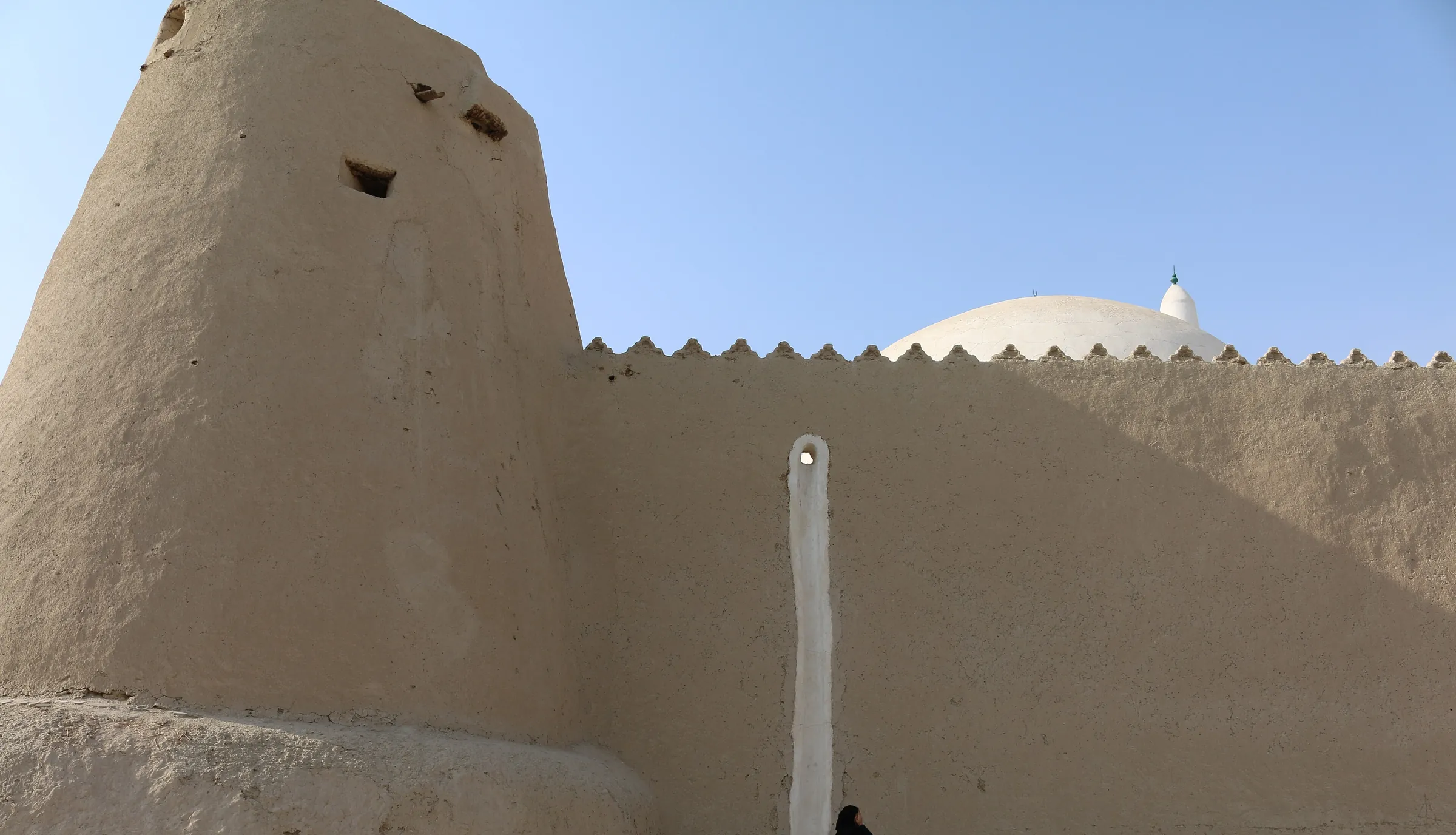 سور قصر إبراهيم الأثري وبرجه الطيني وقبة المسجد خلفه